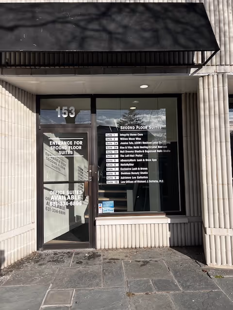 Building entrance with glass door and signage for second-floor suites, address 153