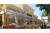 Exterior view of Alamitos West Health & Rehabilitation with beige walls and white pergola.