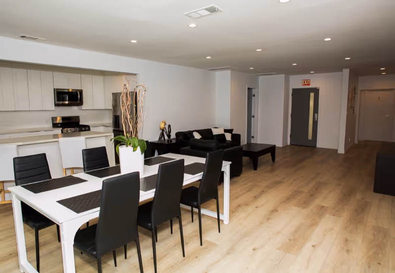Open-concept common area with a white dining table, black chairs, and a living room.