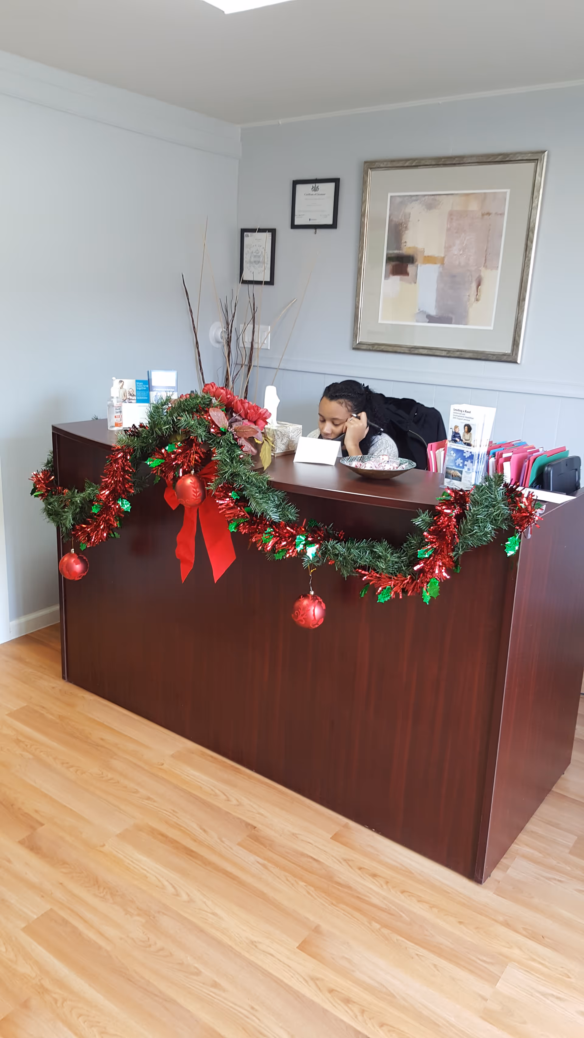 A staff member sits behind a decorated reception desk with holiday garland.