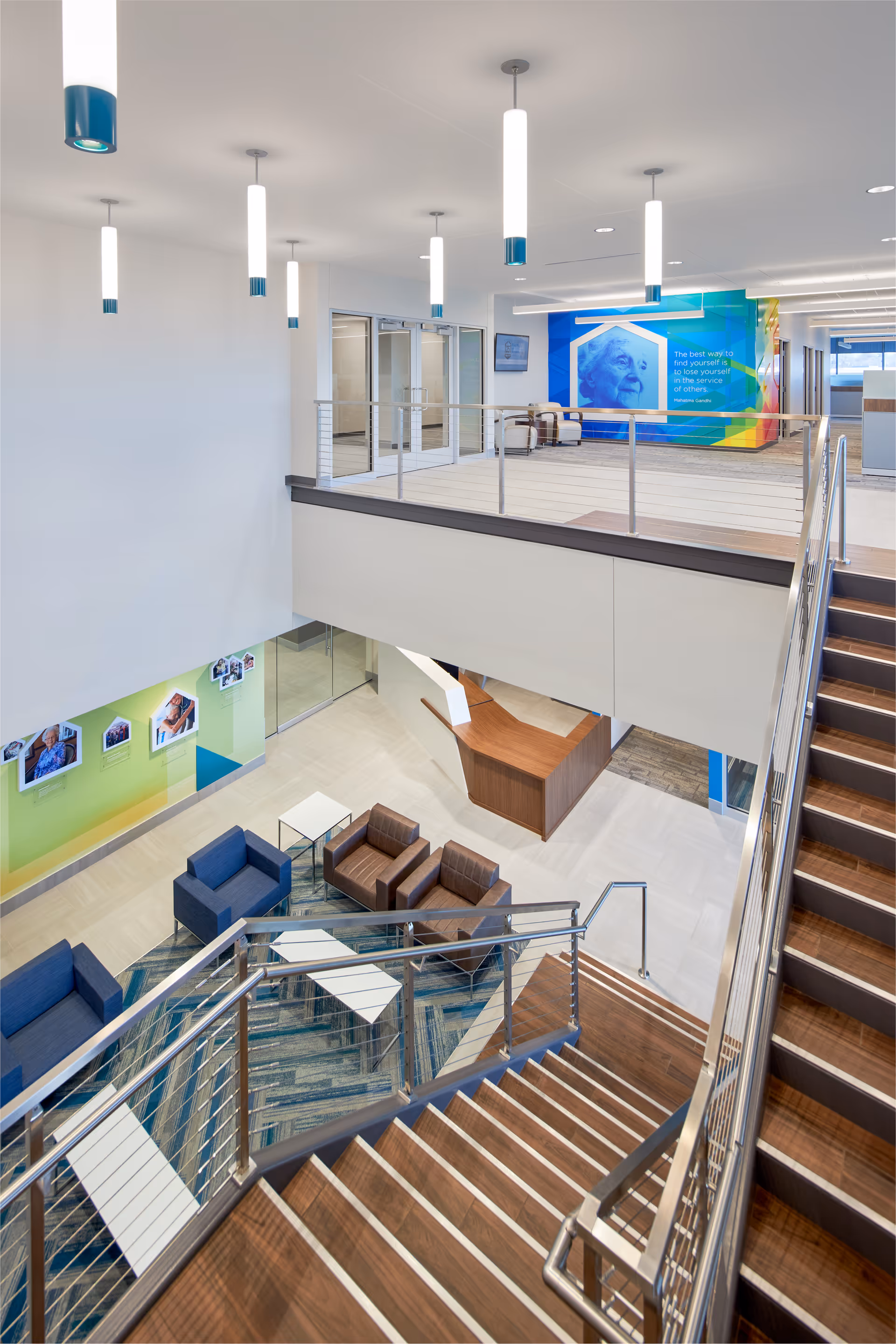 Modern multi-level lobby with glass staircases, seating area, and colorful mural.
