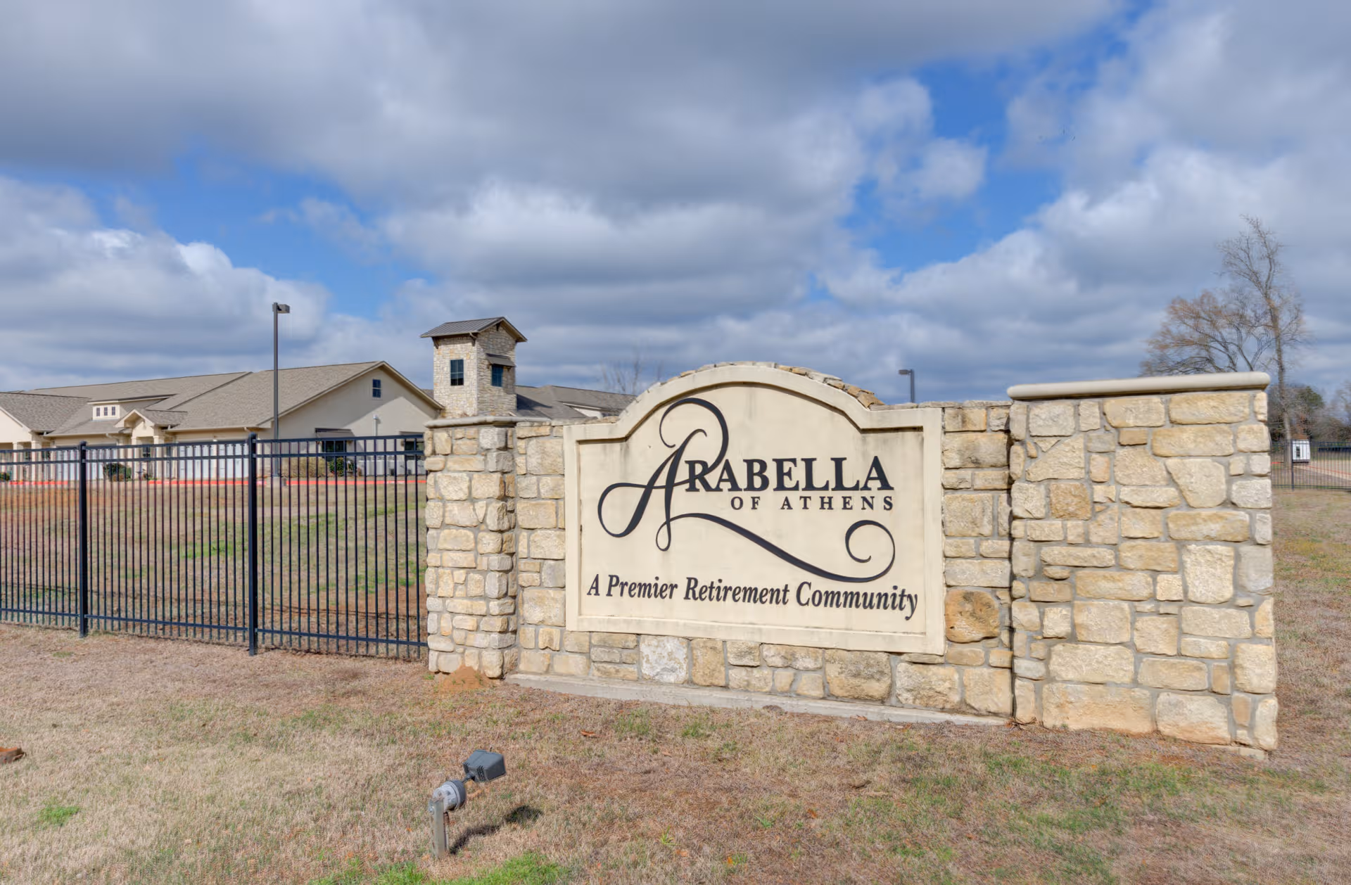 Exterior view of Arabella of Athens retirement community sign on a stone wall.