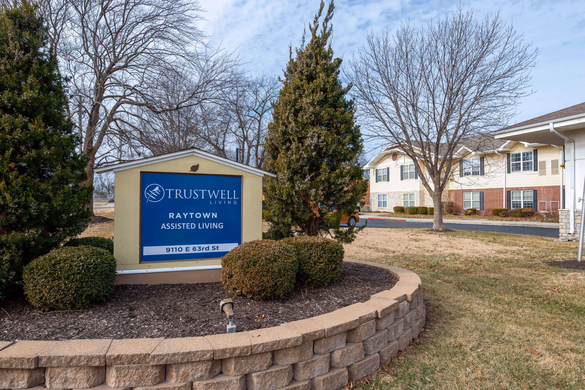 Exterior view of Trustwell Living Raytown sign and adjacent building.