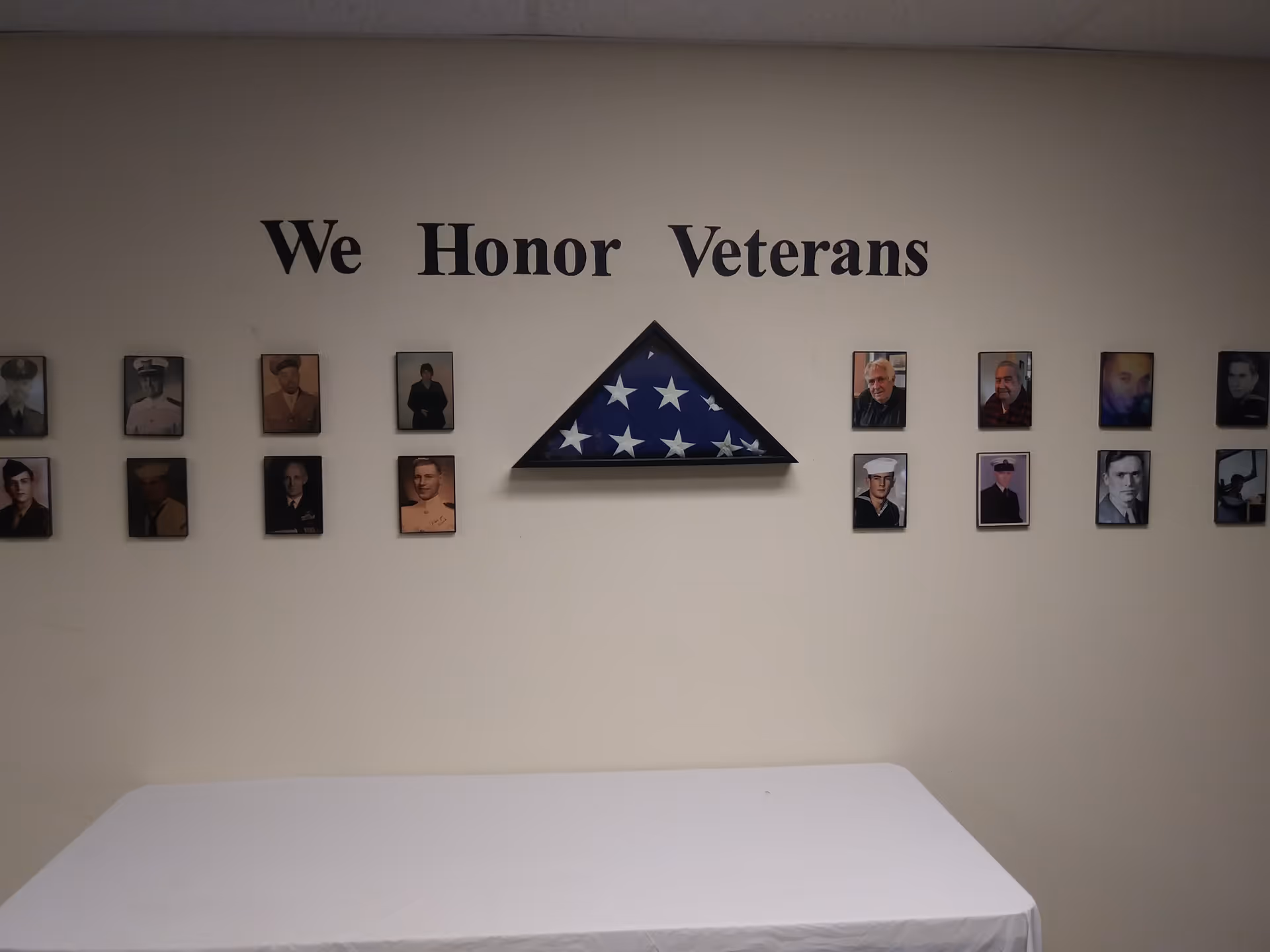 Wall display titled We Honor Veterans with framed photos and a triangular flag centerpiece.