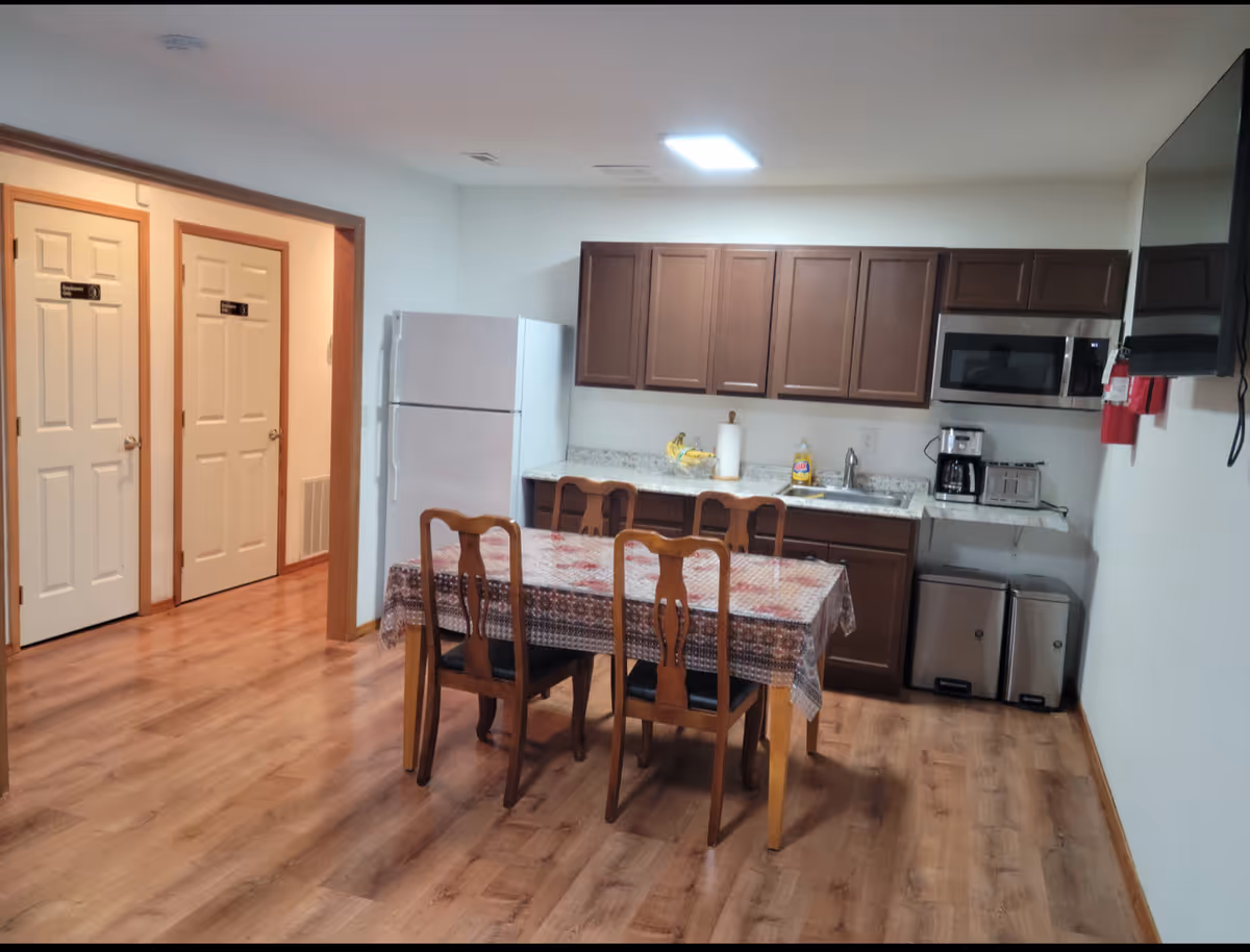 Open dining area with a wooden table and chairs beside a compact kitchen.