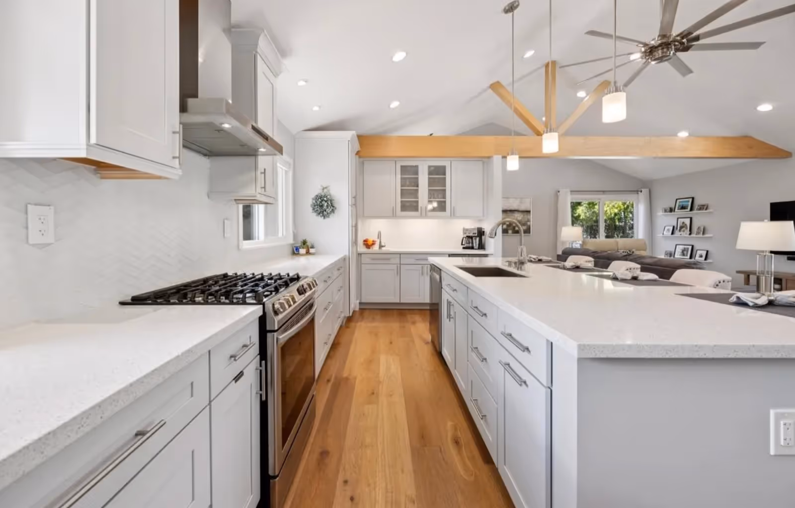 Bright spacious kitchen with white cabinets, island, stainless appliances, and open living area.