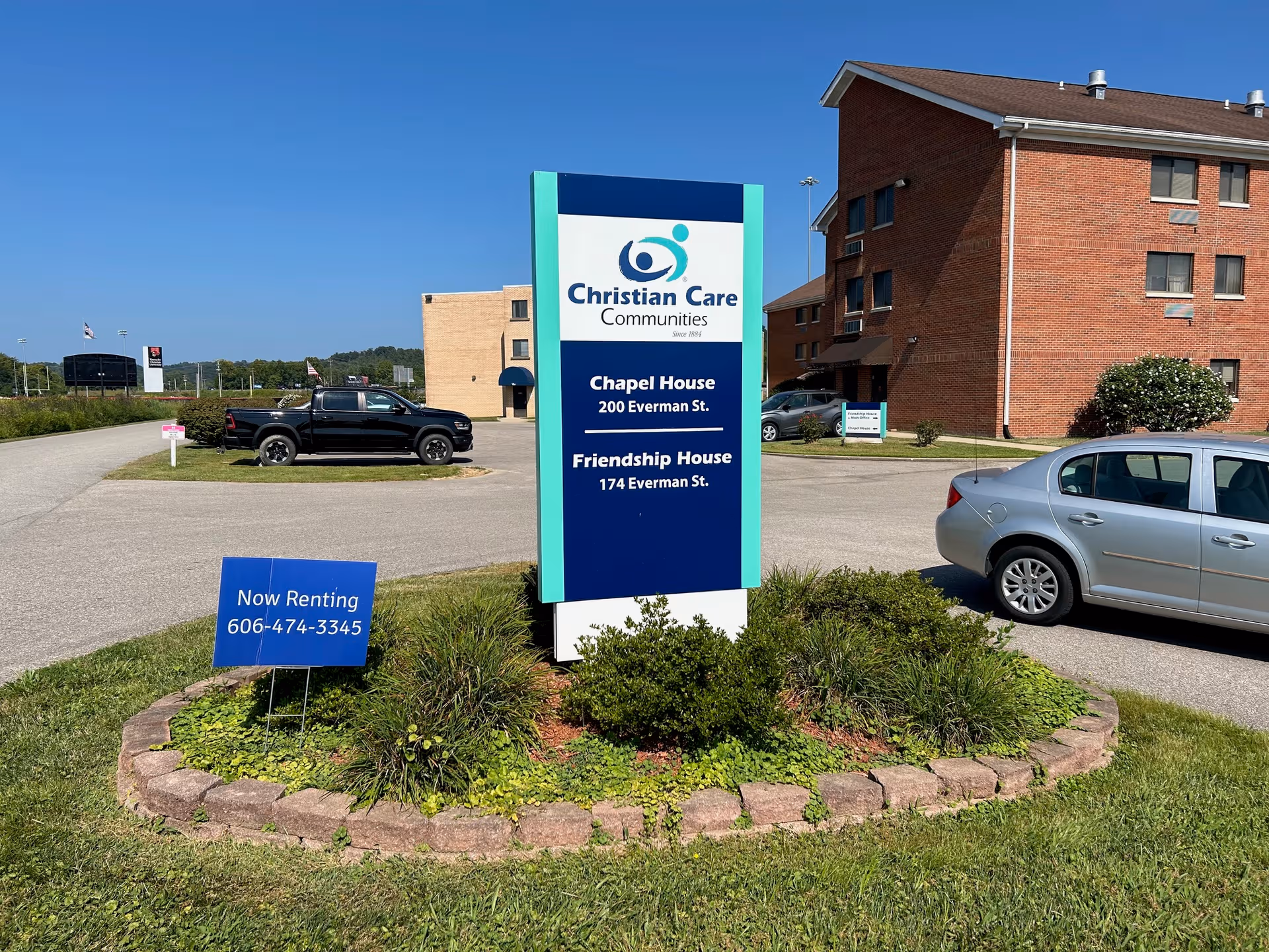 Christian Care Communities sign for Chapel House and Friendship House with brick building in background.