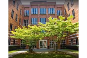 Brick Linden Center building courtyard with green trees and a central doorway.