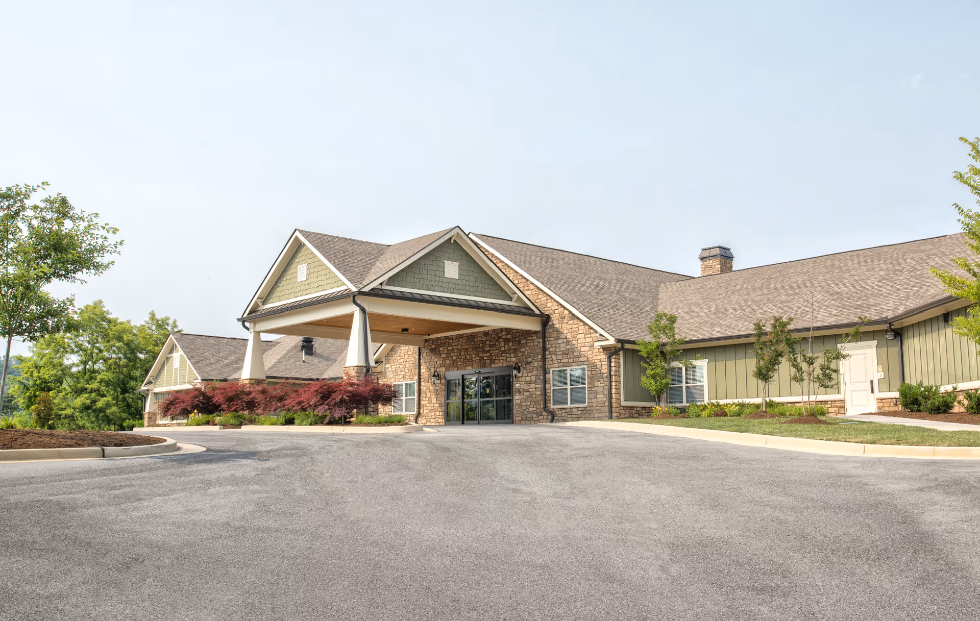 Front exterior of a single-story senior living facility with a porte-cochere entrance and landscaping.
