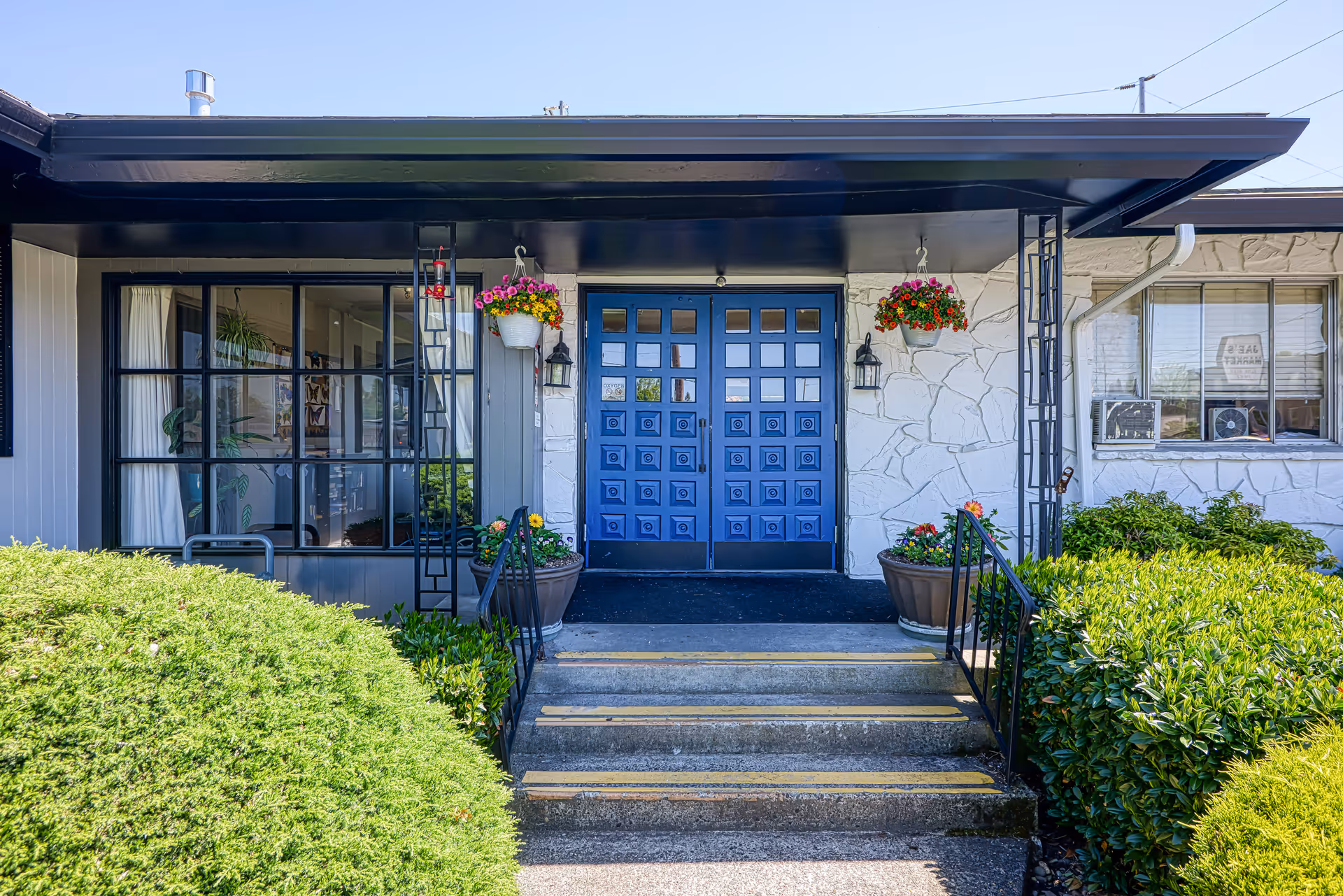 Front exterior of Creekside Rehabilitation and Nursing with a blue door, hanging planters, and steps.