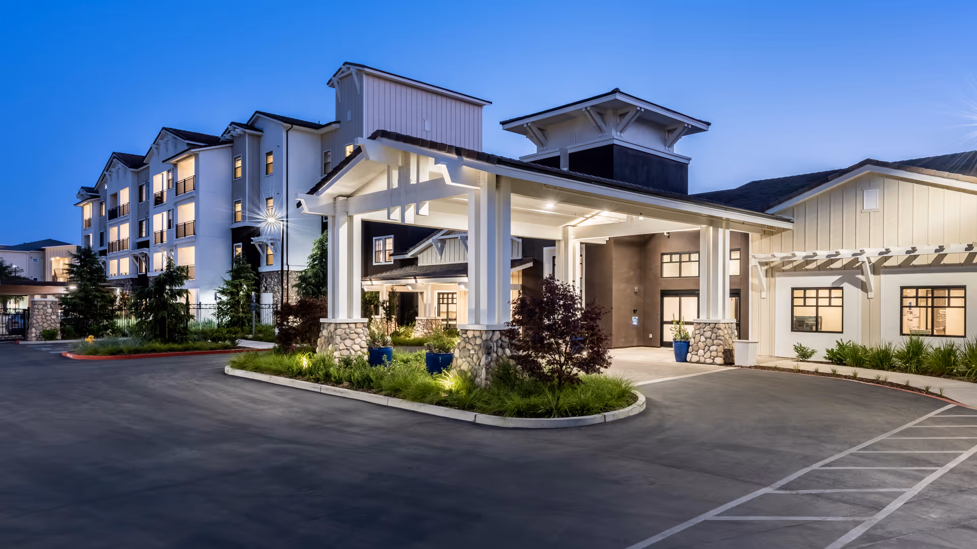 Exterior view of Revel Lodi senior living facility with driveway, porte-cochère, and landscaped entrance.