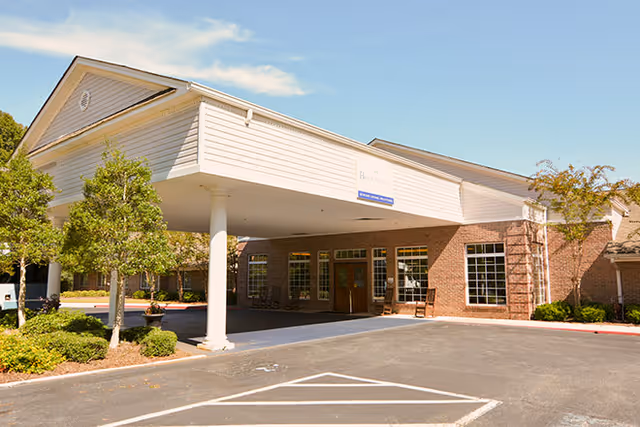 Front exterior of Serenity Empire showing the covered entrance/porte-cochère, brick facade, windows, and surrounding landscaping.