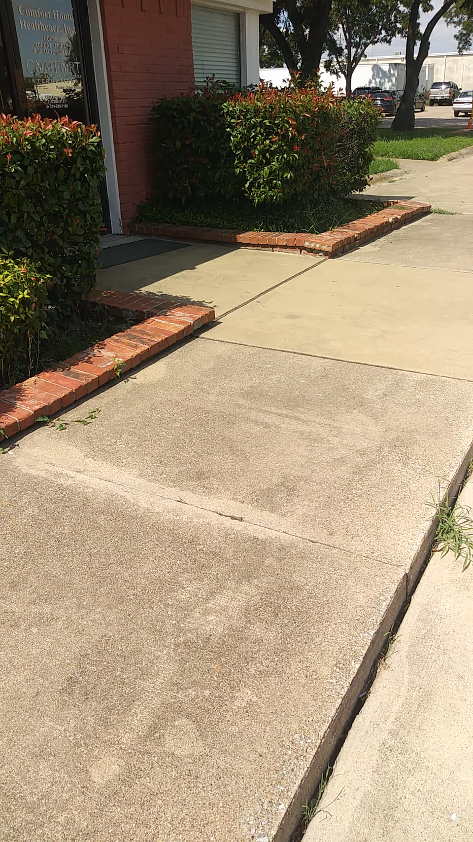 Exterior view of the entrance with shrubs, brick edging, and sidewalk.