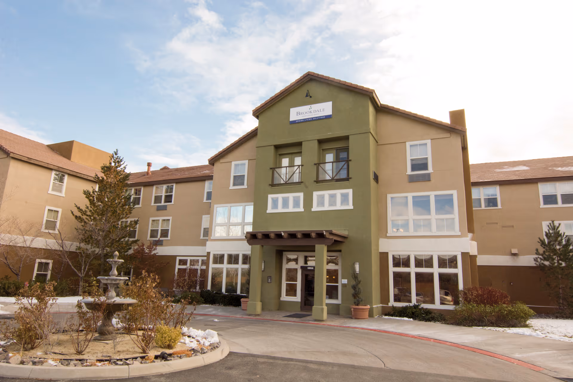 Exterior view of a multi-story senior living building with a covered entrance