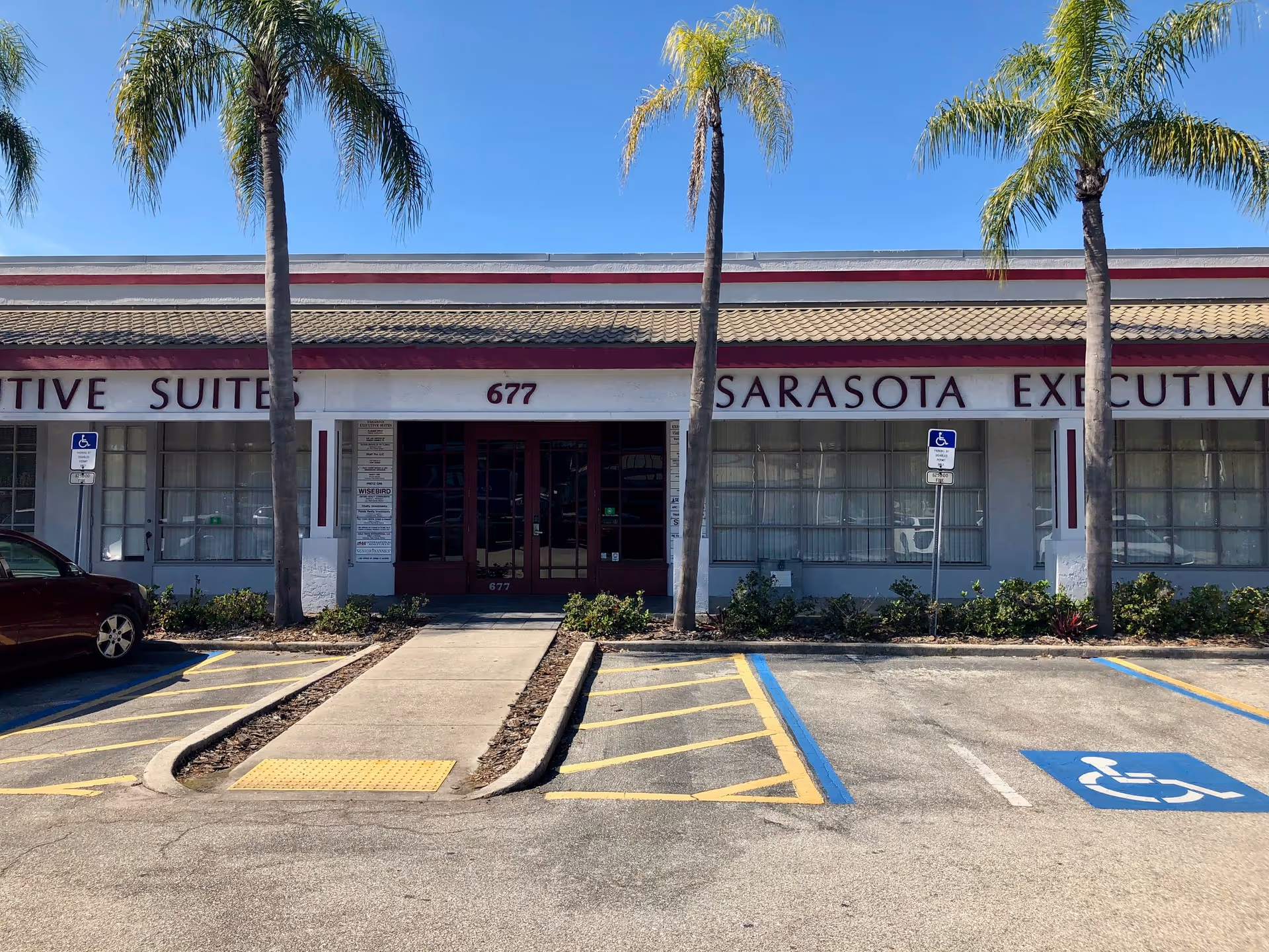 Front view of a single-story building with palm trees and accessible parking spaces.