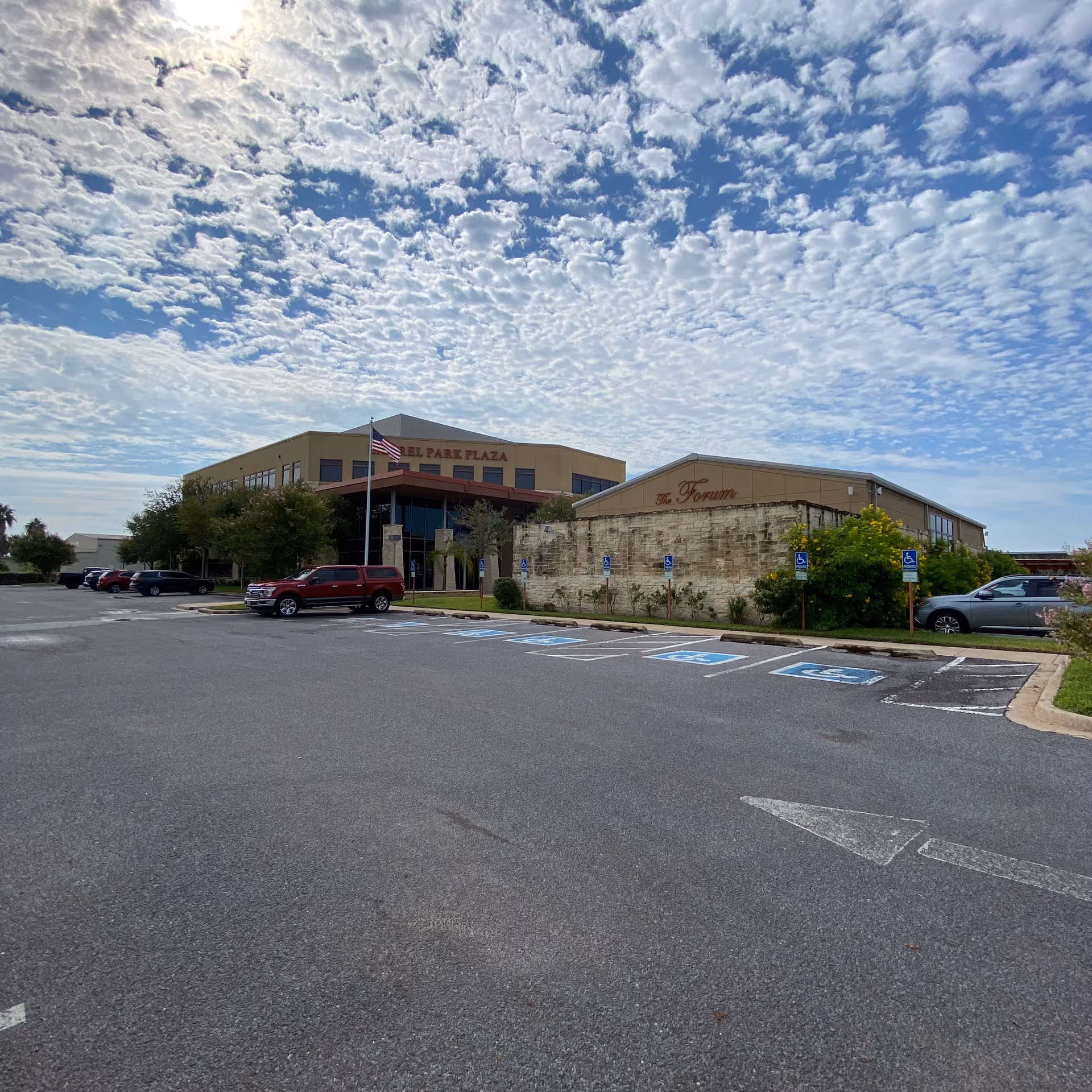 Exterior view of a beige healthcare facility with a parking lot and handicap spaces.