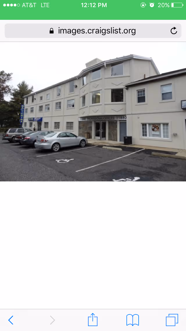 Beige multi-story building with a small parking lot and several cars in front.