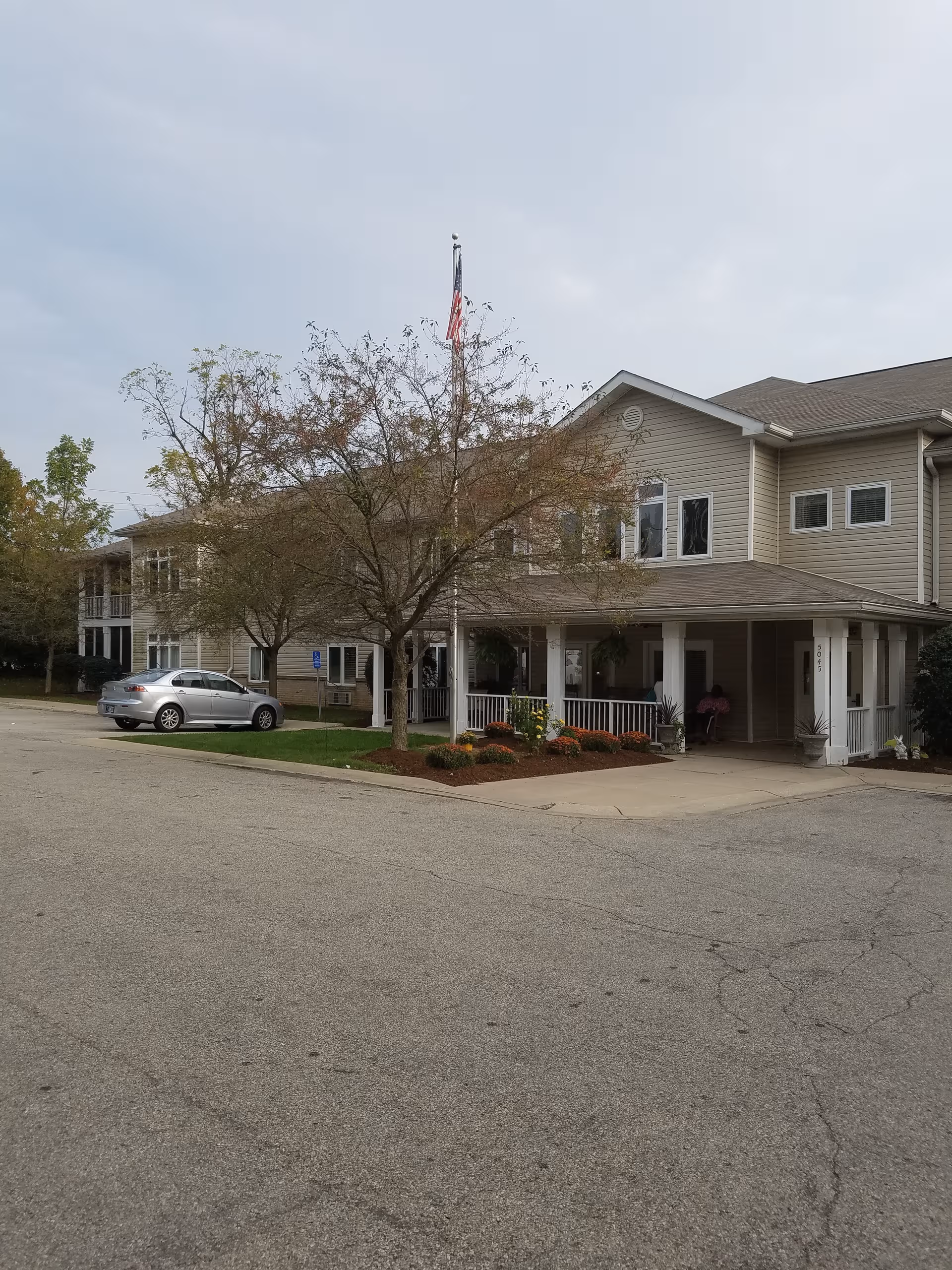 Exterior view of Bloom at Eagle Creek, a two-story senior living building with porch and landscaping.