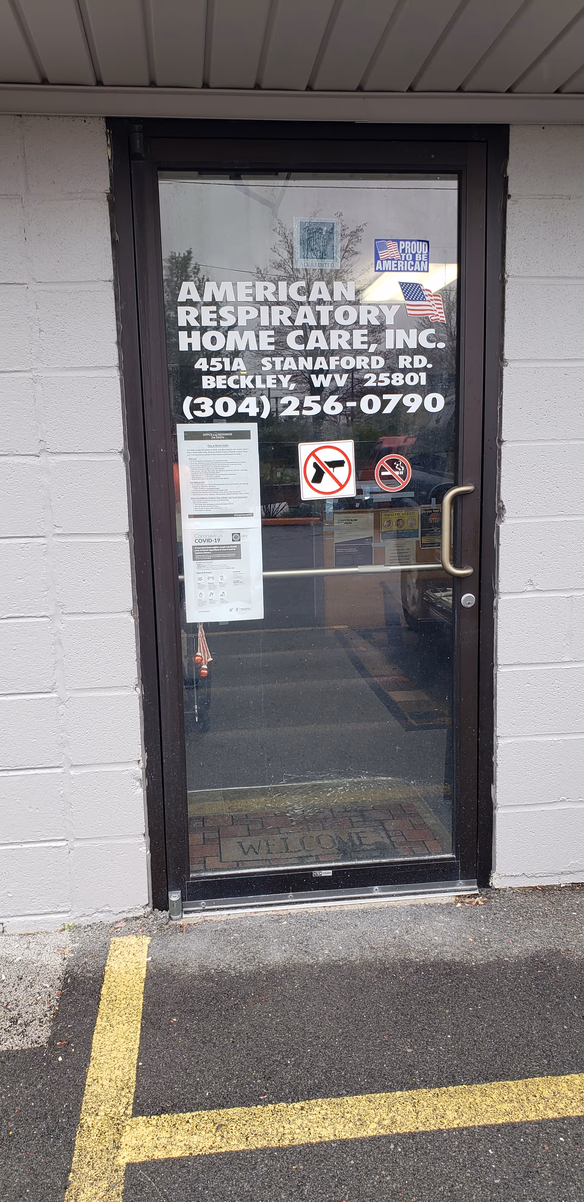 Glass front door with signage for American Respiratory Home Care on a gray exterior wall.