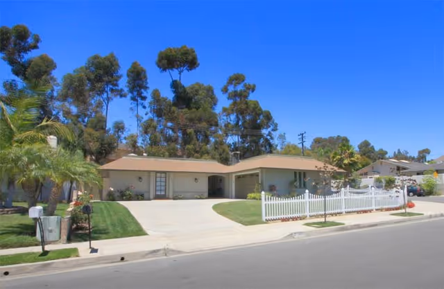 Front exterior of John Scott House Nursing and Rehabilitation Center with a driveway and palm trees