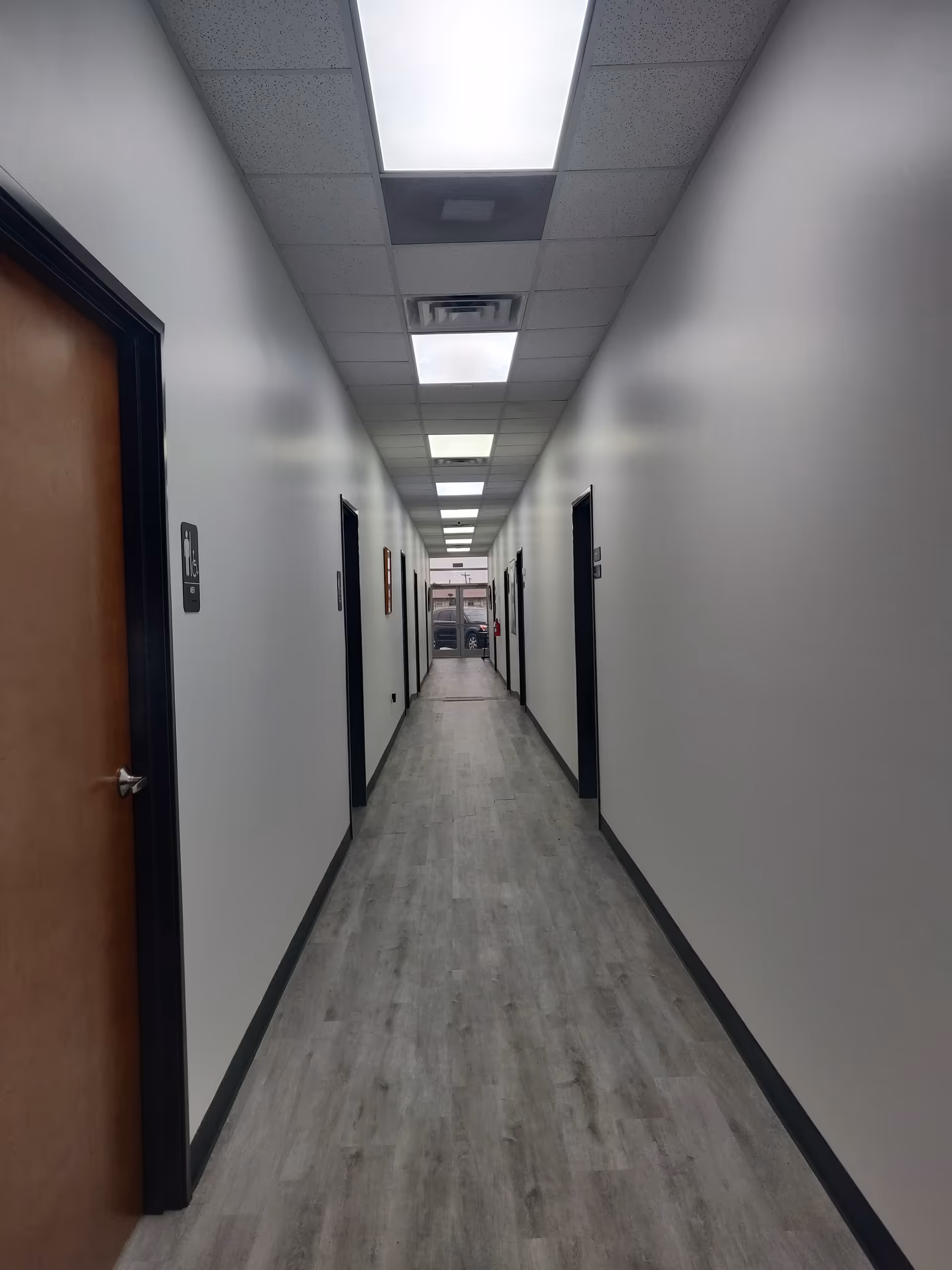 A long, empty corridor in a senior living facility with doors on both sides.
