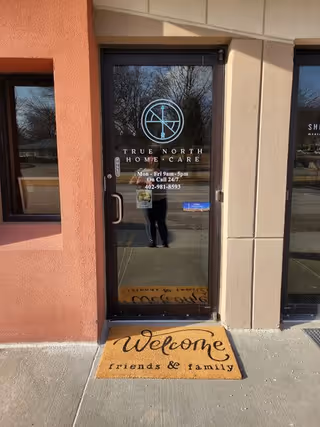 Glass entrance door with True North Home Care logo and welcoming mat outside.