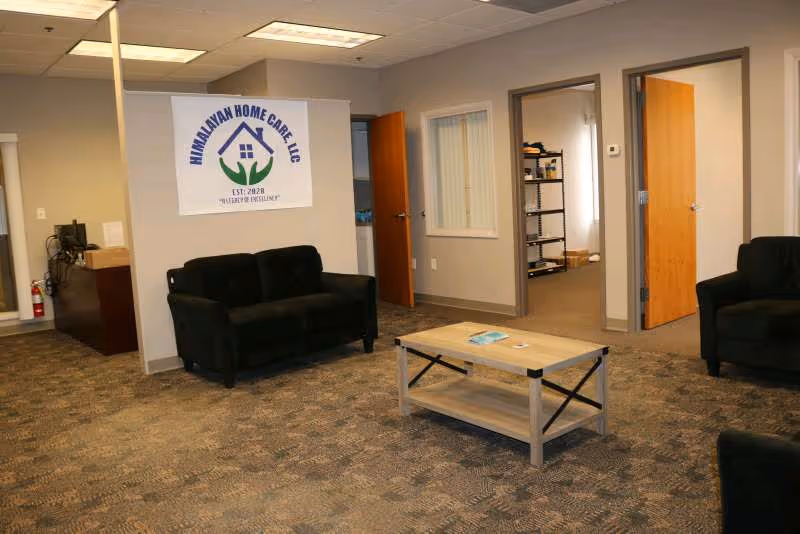 Interior common area with black couches, a wooden coffee table, and a Himalayan Home Care banner.