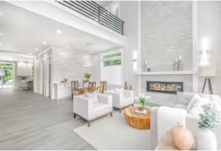 Bright modern living area with white furniture, fireplace, and a dining nook.