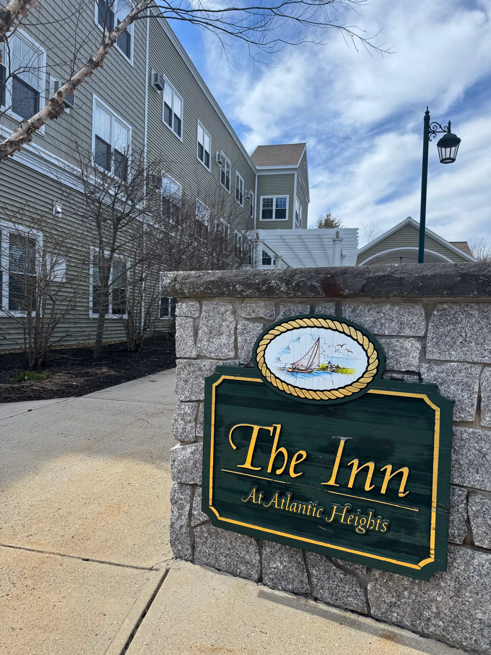 Exterior view of The Inn at Atlantic Heights with a stone sign and green building.