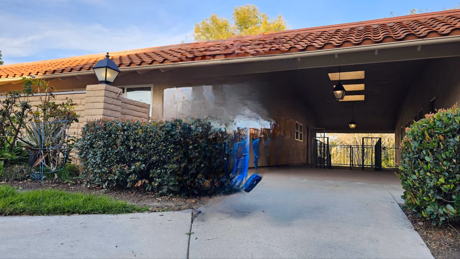 Exterior view of a covered entrance with shrubs and a gate at Laguna Woods Village.