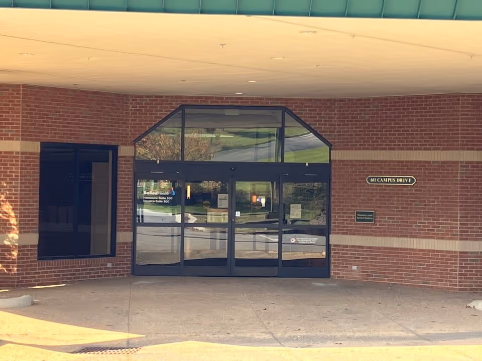 Brick-front entrance of Ballad Health Home Health with glass doors under a covered drop-off.