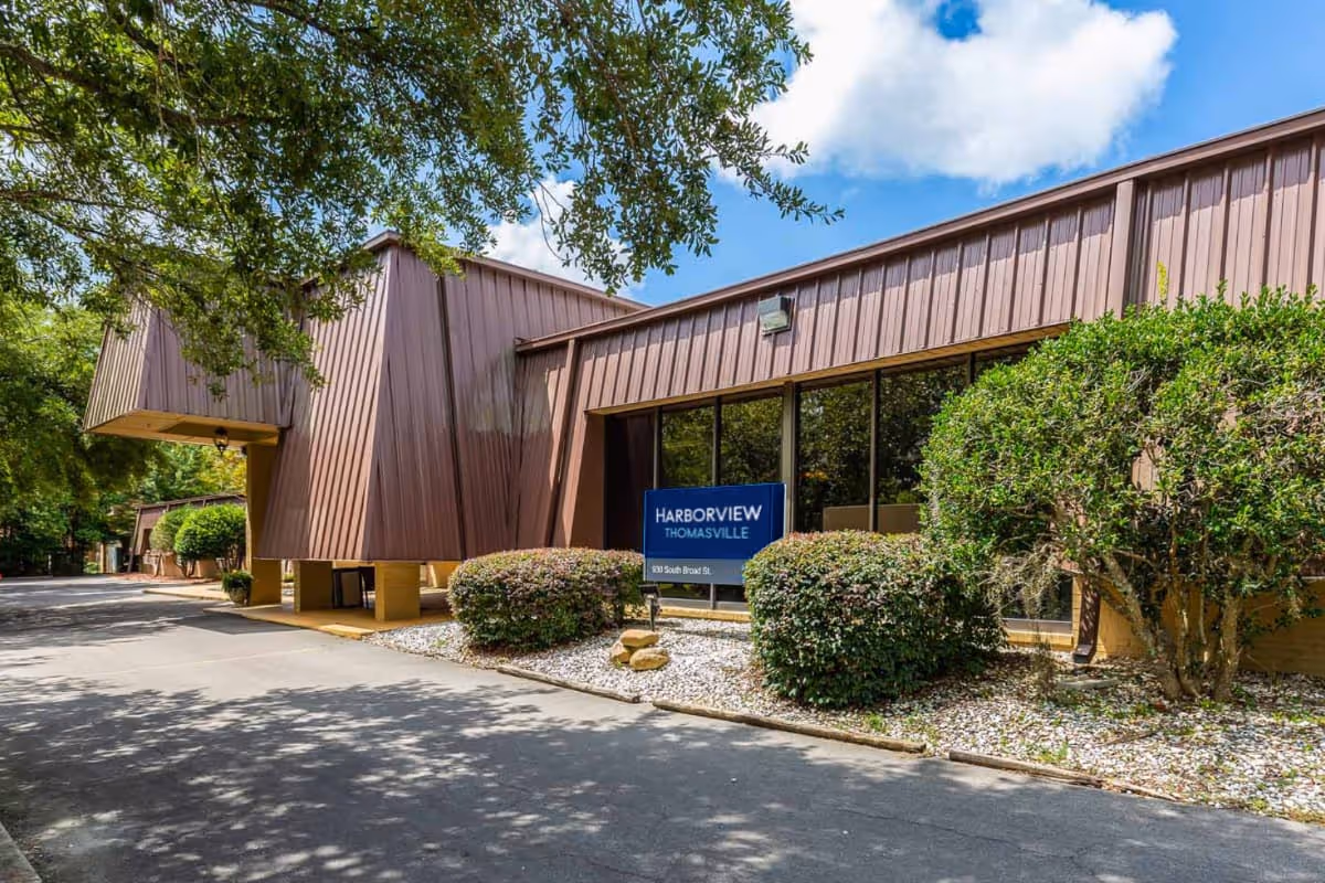 Exterior view of Harborview Thomasville with brown metal building, sign, and landscaped surroundings.