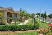 The Arbor Faire Senior Apartments front exterior shows a manicured lawn and walkway.
