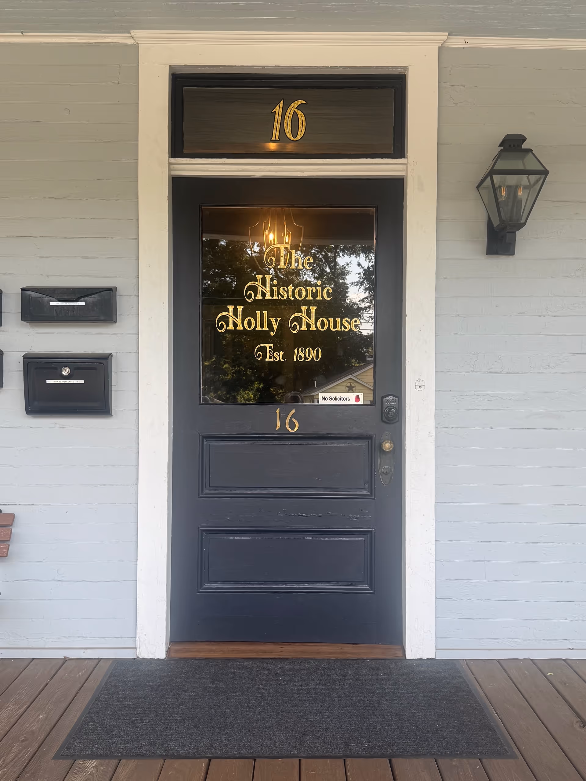 Dark front door with gold lettering reads The Historic Holly House, Est. 1890, 16 on door.