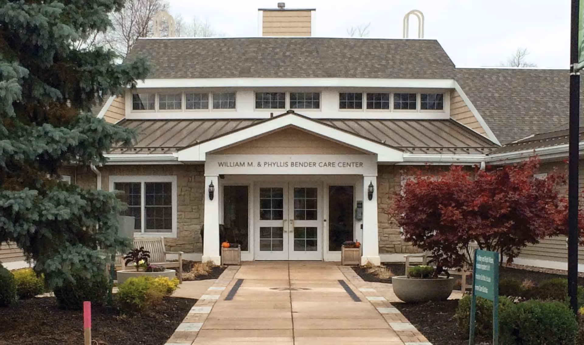 Front view of a care center entrance with walkway, trees, and planters.