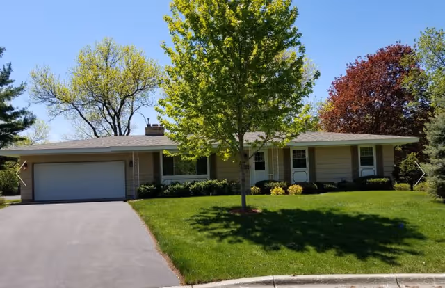 Front exterior of a single-story senior living home with a green lawn.