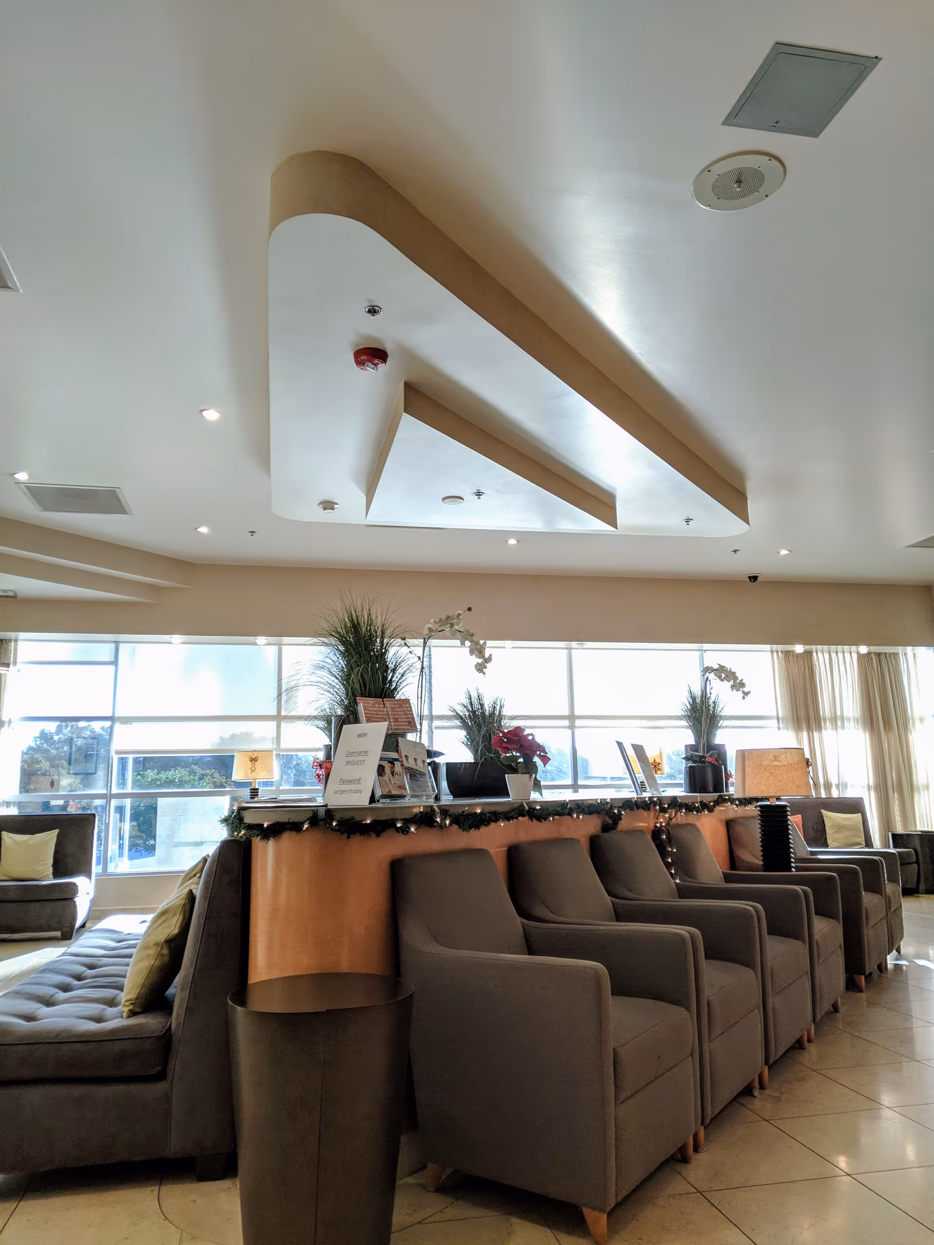 Spacious senior living lobby with row of gray chairs, decorative garlands, and a reception desk.