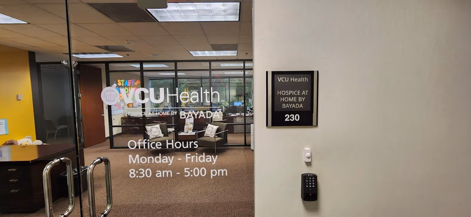 Entrance lobby with glass doors displaying VCU Health Hospice at Home by BAYADA and office hours.