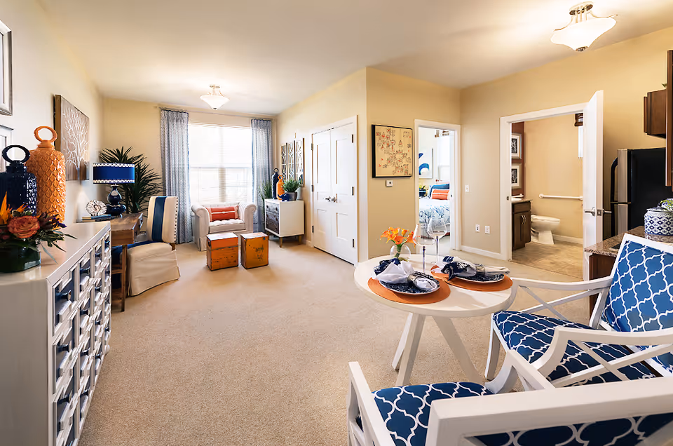 Bright senior living living room with blue-patterned chairs, a round table, and decorative accents.