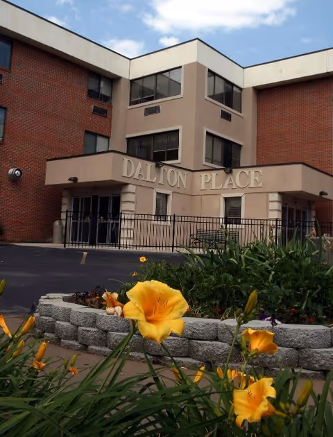 Exterior view of Dalton Place, a brick senior living building with flowers in foreground.