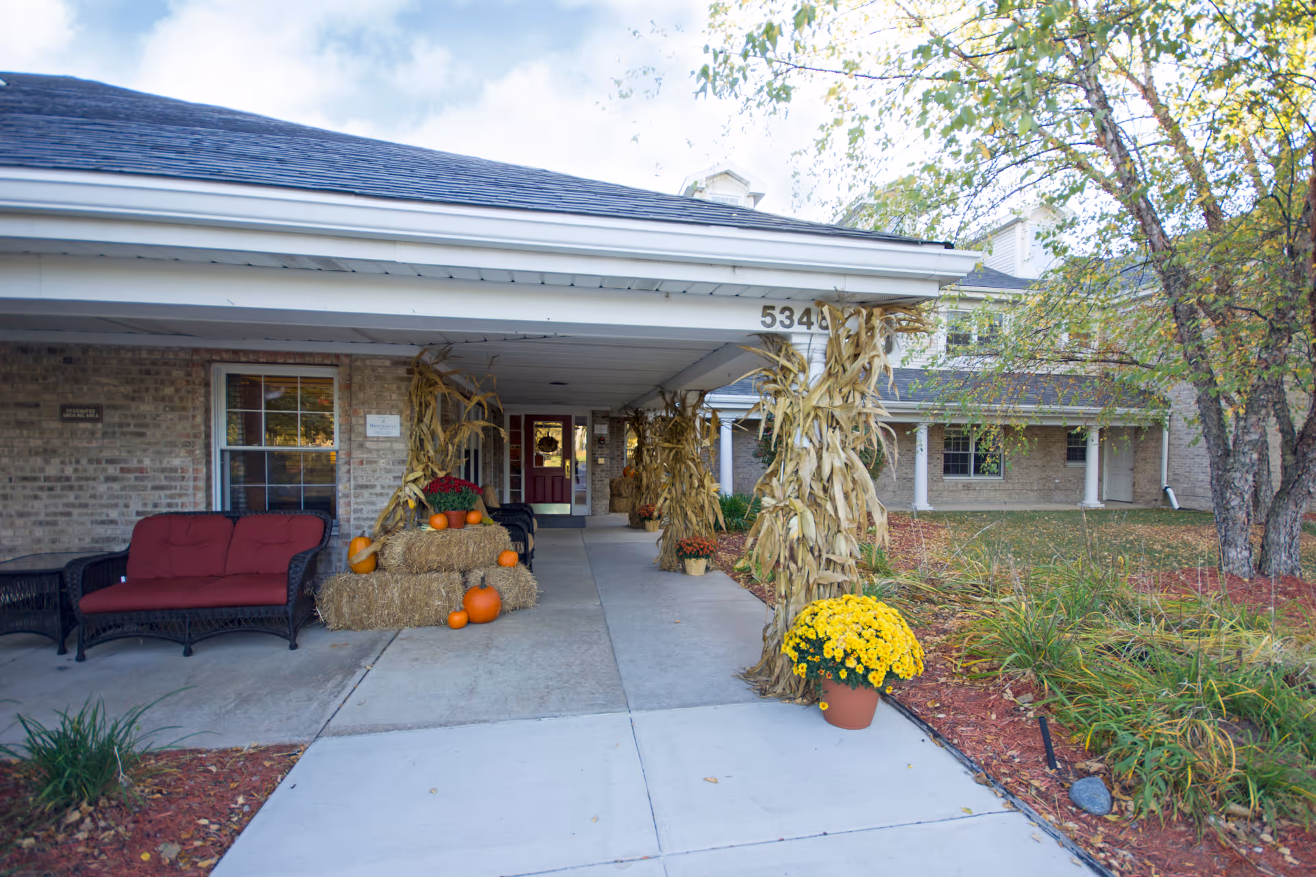 Front entrance of Brookdale Meridian Assisted Living with fall decorations, pumpkins, hay bales, and seating.