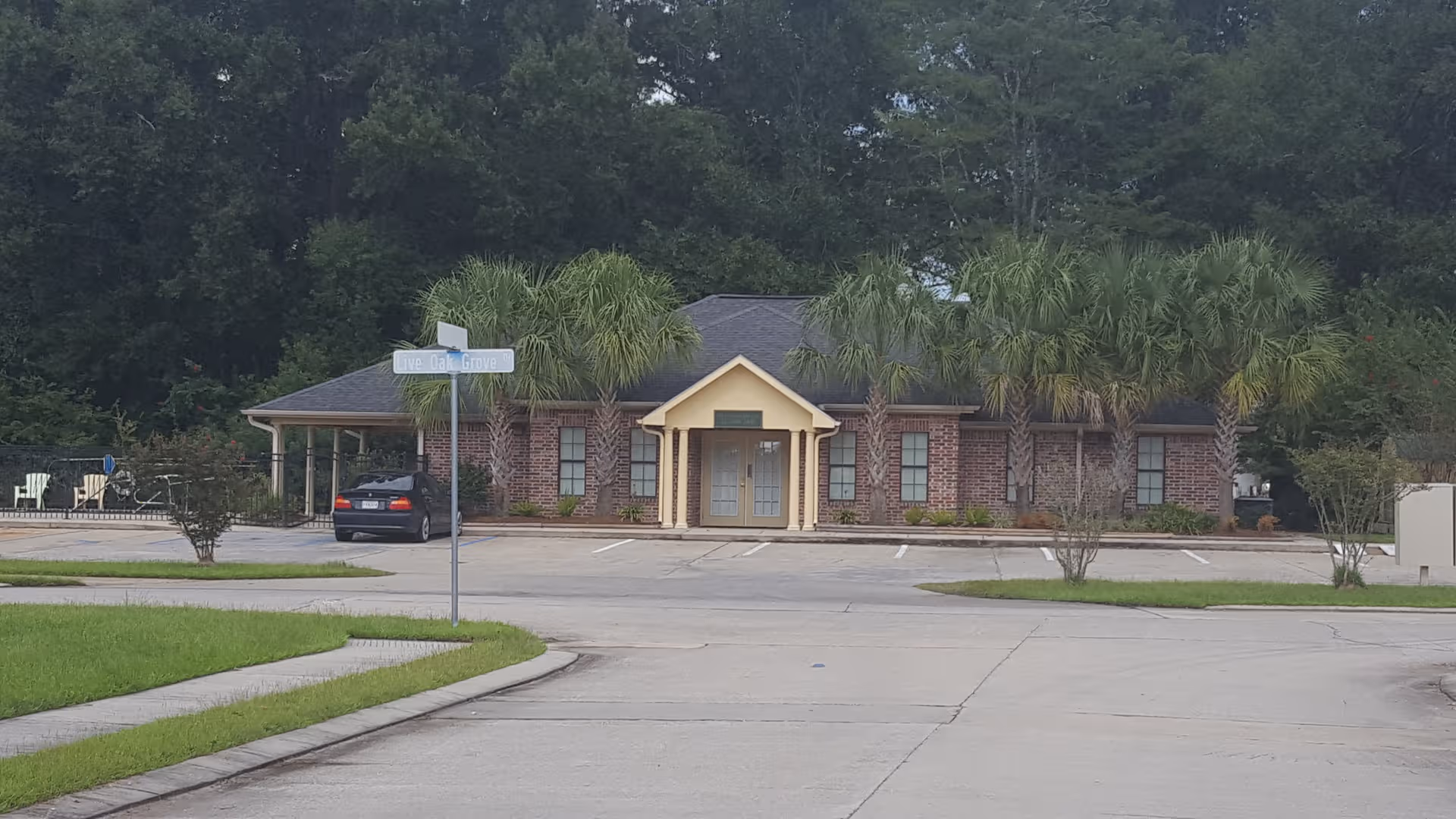 Brick senior living facility with palm trees, front entrance, and a parking lot.
