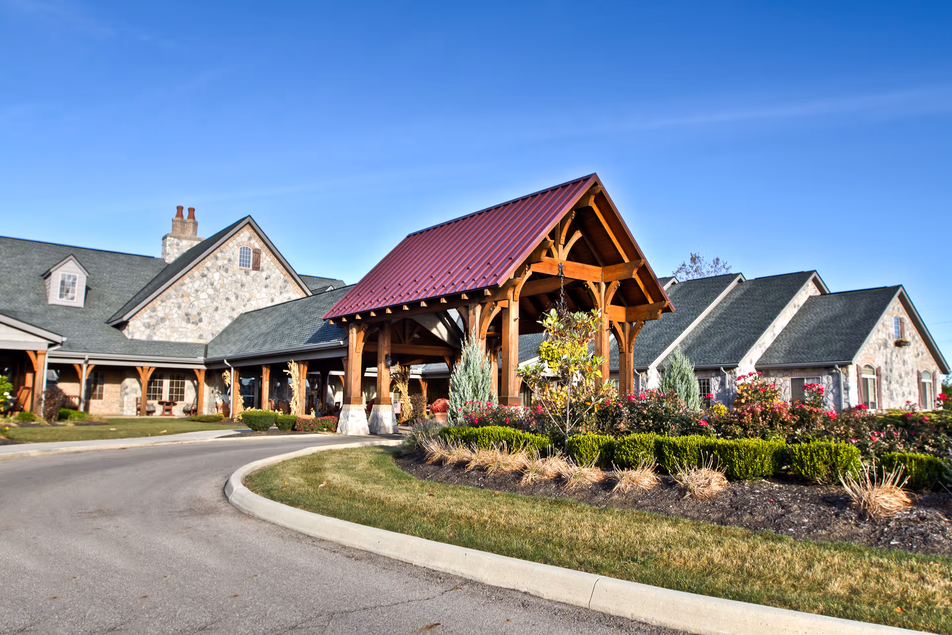 Stone-faced senior living facility with a wooden entry canopy and landscaped grounds.