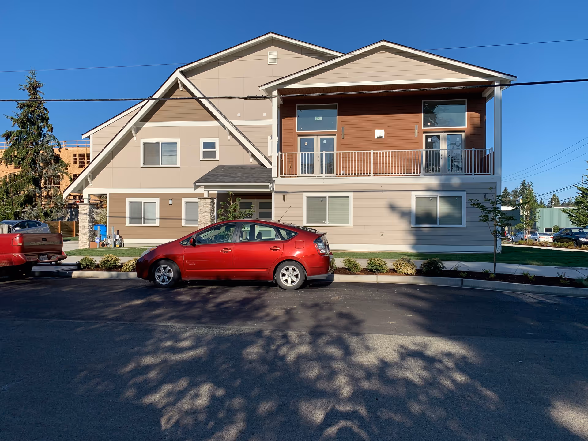A modern two-story senior living facility with beige siding and a red car out front.