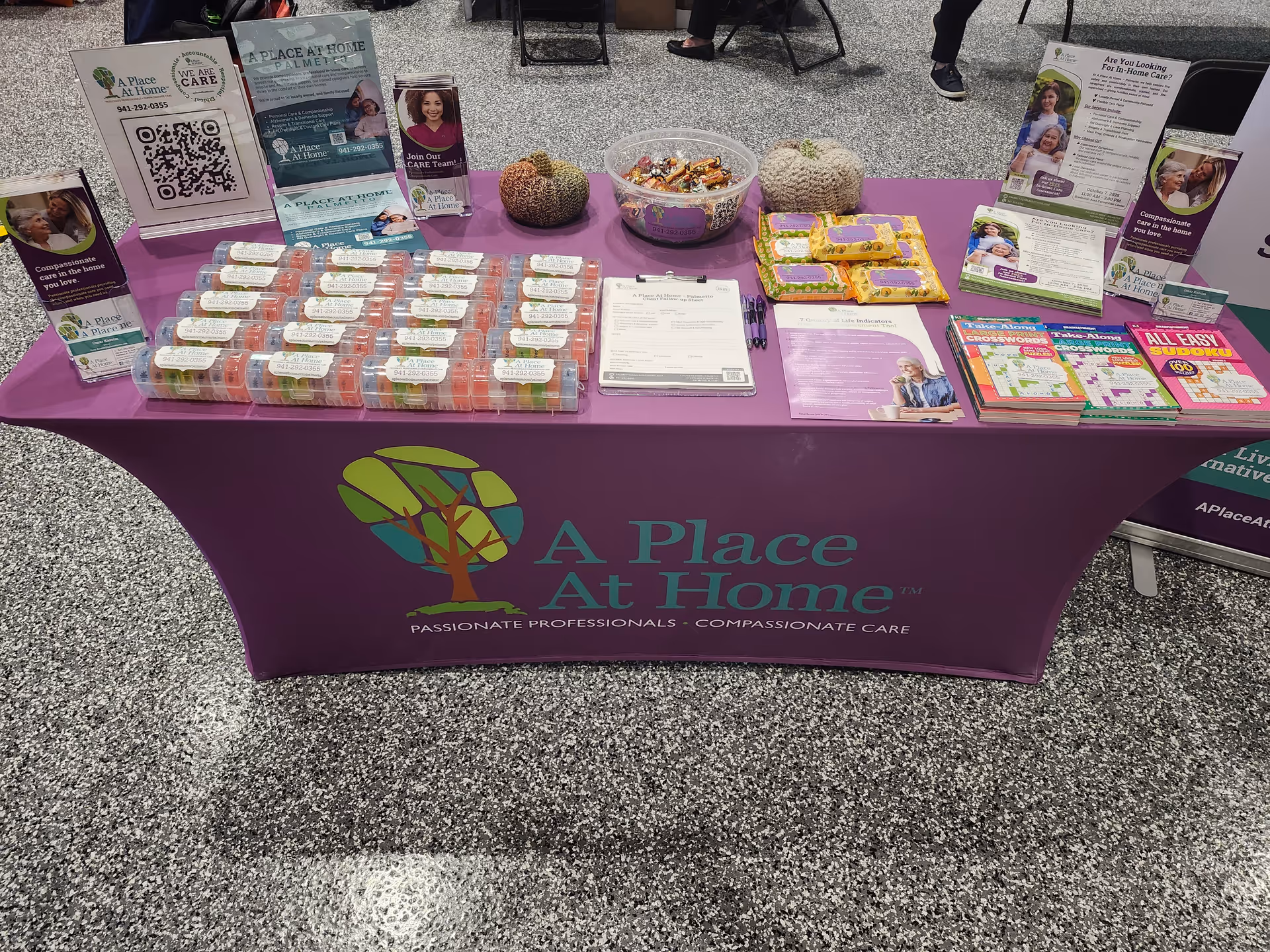 Promotional table with purple cloth and brochures for A Place At Home Palmetto in a hallway
