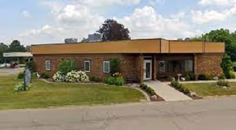Single-story brick senior living building with a front entrance and landscaped walkway.