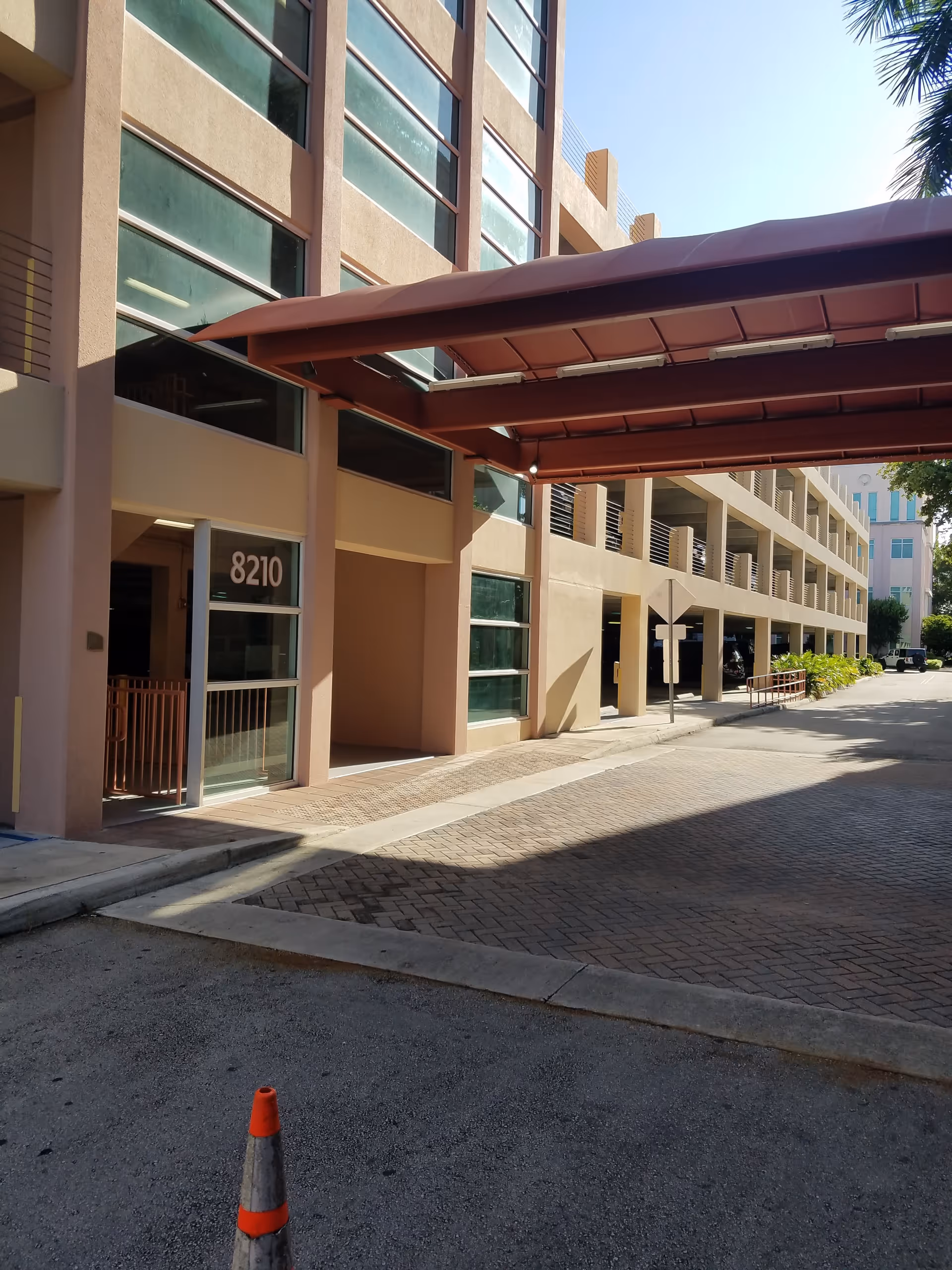 Exterior view of a multi-story building entrance with a brown canopy and sidewalk.