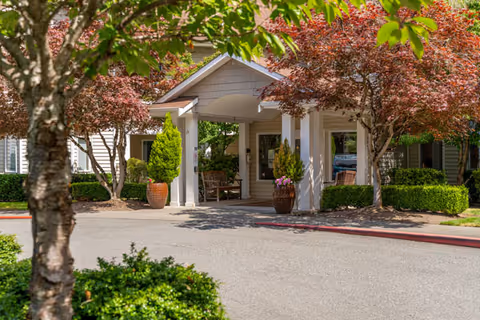 Front entrance of Patriots Glen senior living facility with a covered porch and potted plants.