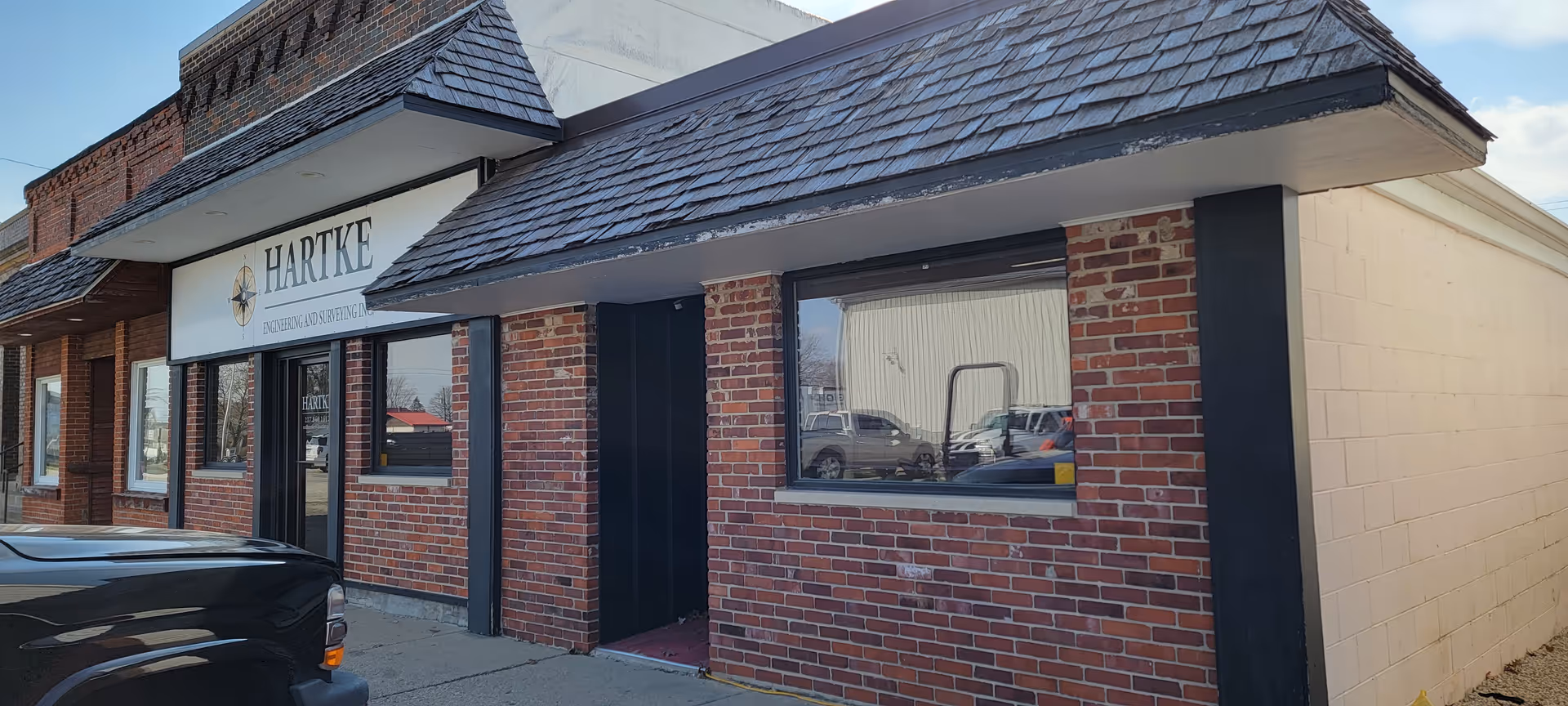 Exterior view of a brick storefront with Hartke sign and large windows.