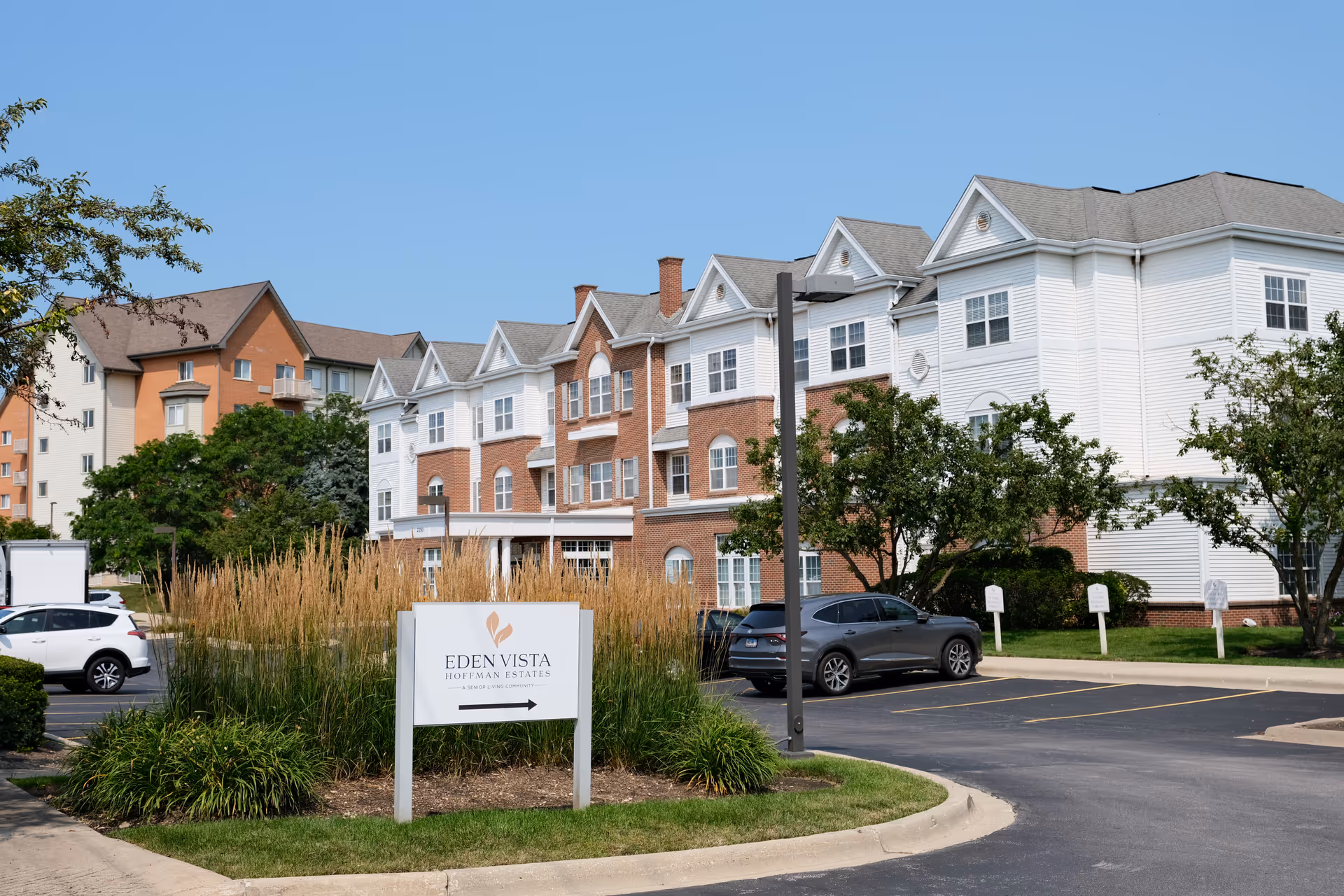 Sign reading 'Eden Vista Hoffman Estates' in front of a multi-story senior living building with a parking lot and landscaping.